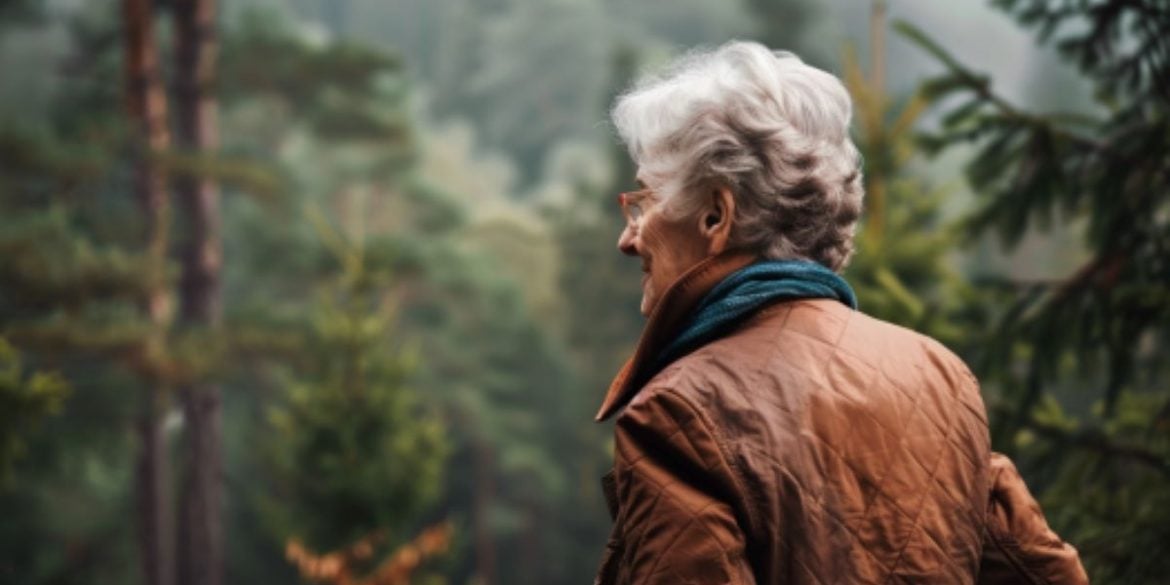 This shows an older woman walking in the woods.
