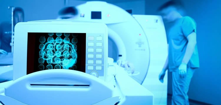 Image of an MRI machine wiht a brain scan on a computer monitor.