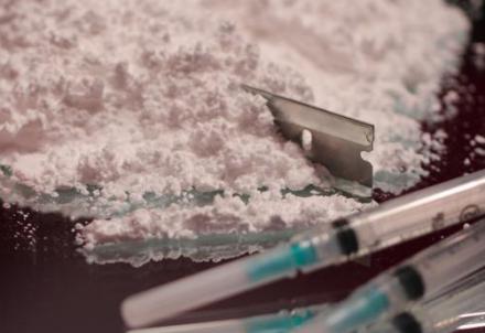 Cocaine with a needles and a razor blade are shown.