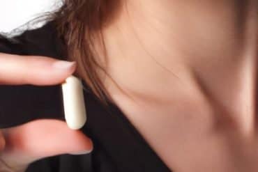 This shows a woman holding a pill