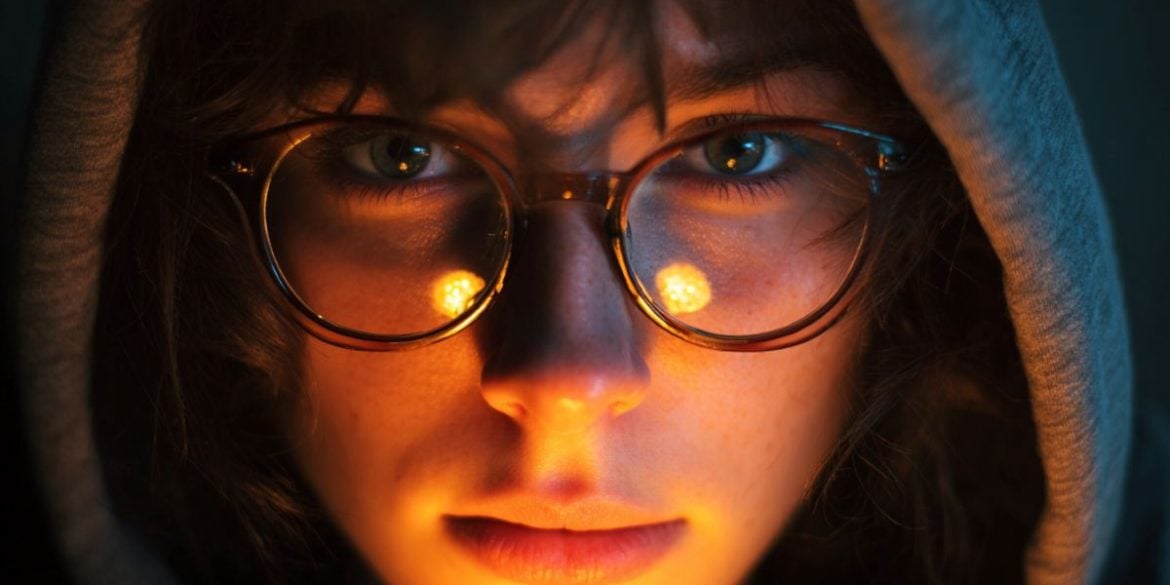This shows a woman wearing glasses. The light around her is dim.
