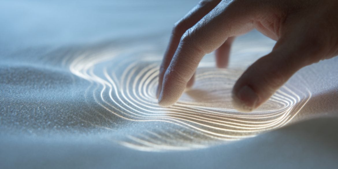 This shows a hand touching sand.