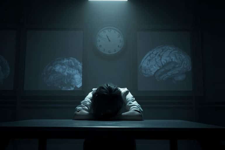 This shows a person in an interrogation room late at night. Brains are behind him.