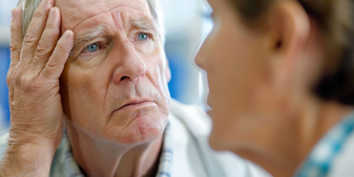 This shows an older man holding his head.