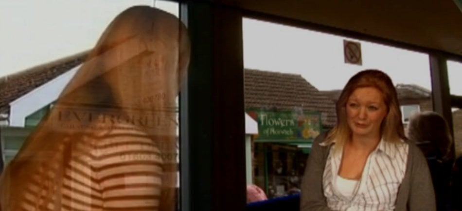 The image is a still of the video and shows a woman interacting with a computer generated person.